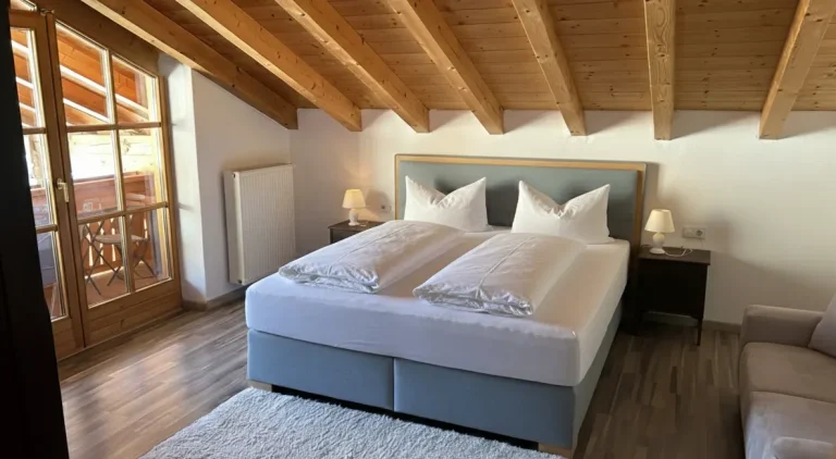 Helles Schlafzimmer mit Doppelbett, Holzdecke und Zugang zu einem Balkon.