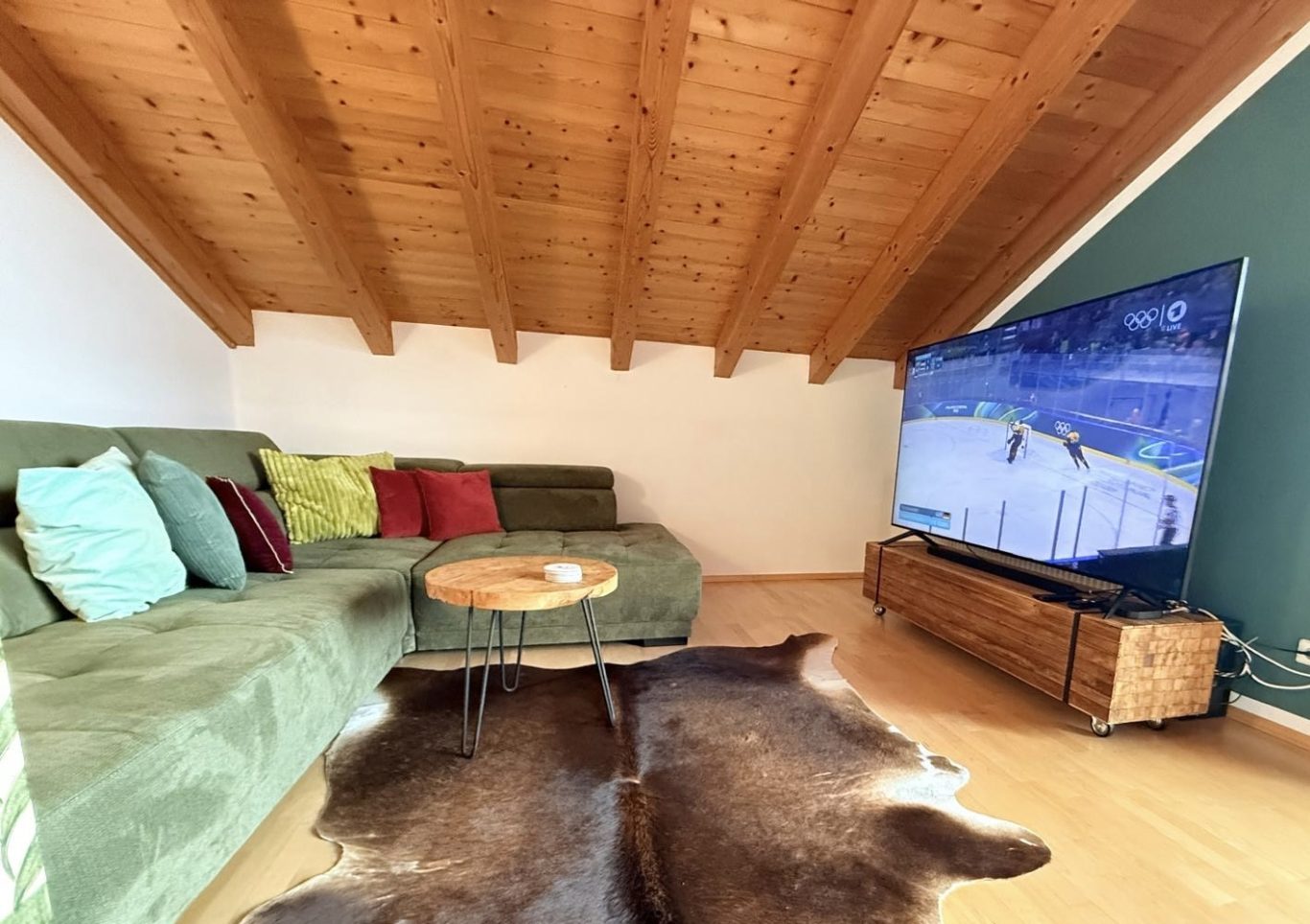 Wohnzimmer Großzügiges Dachgeschoss-Wohnzimmer mit elektrischem Kachelofen und gemütlicher Couch im Haus am Wiesbach.