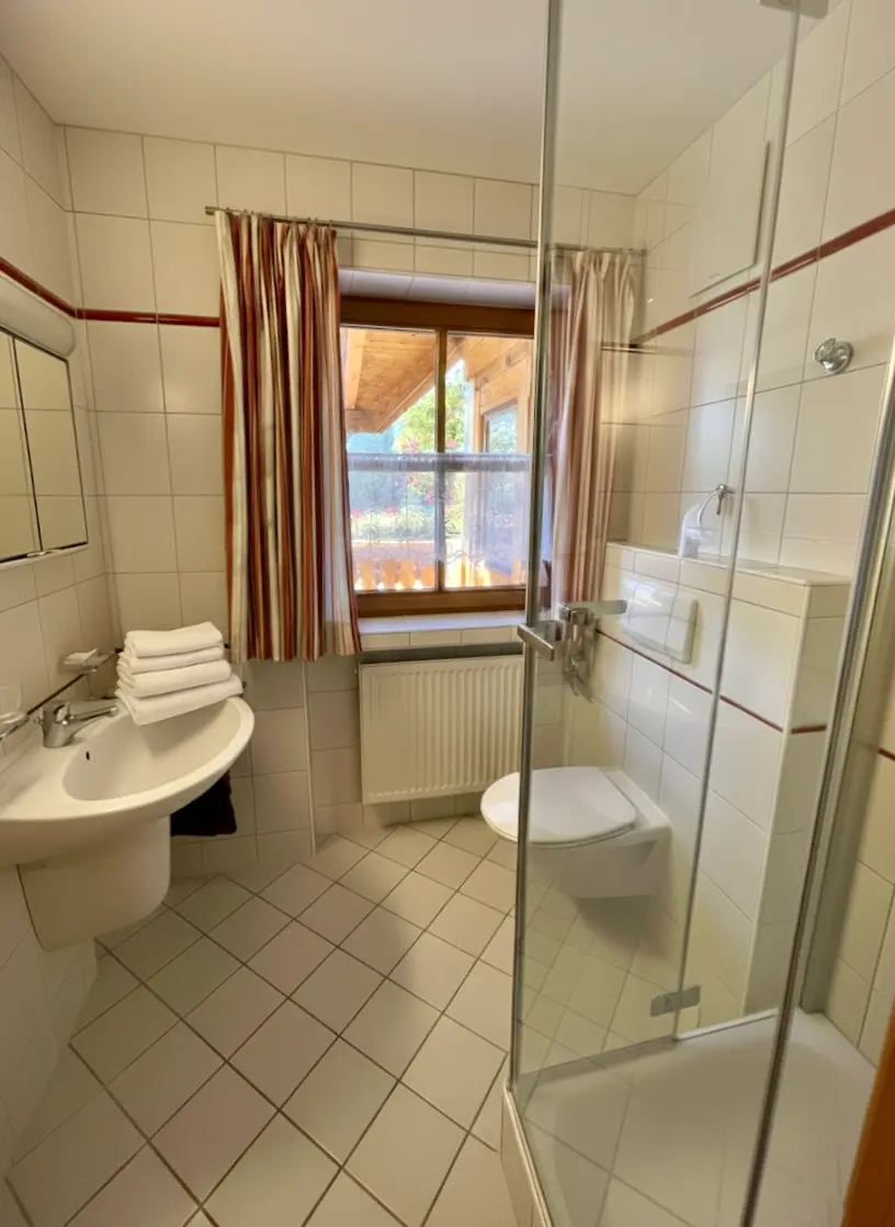 Badezimmer Alpenrose Helles, gepflegtes Badezimmer mit Dusche, Föhn und frischen Handtüchern in Boutique Ferienwohnung Alpenrose Haus am Wiesbach.