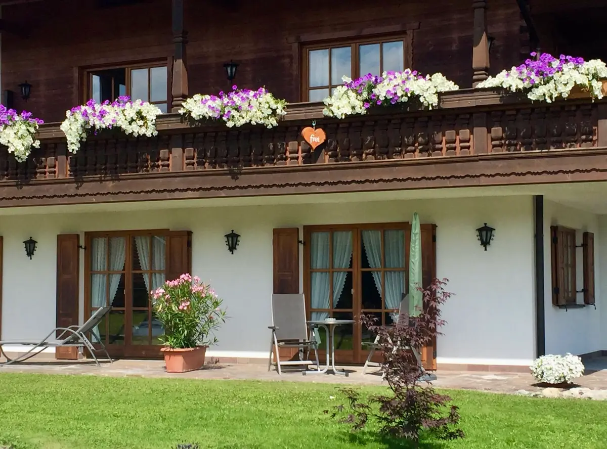 Terasse mit Gartenzugang und Bergblick Terrasse der Ferienwohnung Enzian in Bayern mit Sonnenliegen, Schirm und Blick auf das Alpenpanorama.
