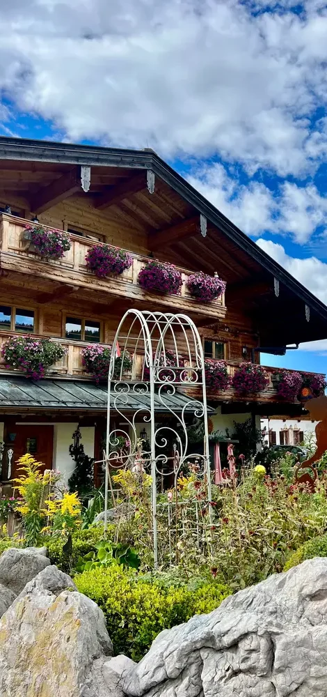 t: Außenansicht vom Haus am Wiesbach in Reit im Winkl mit blühendem Garten und Bergblick während der Zwischensaison.