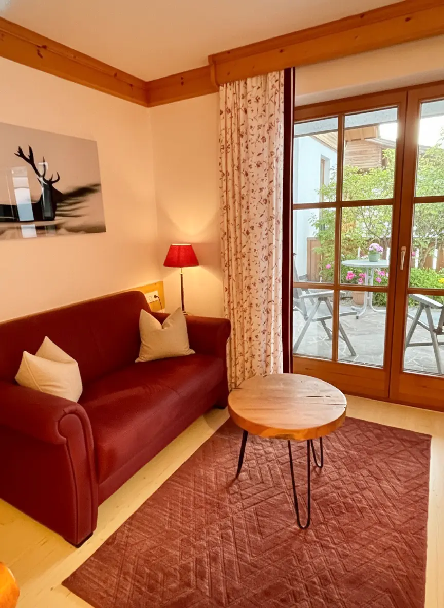 Gemütliches Wohnzimmer Bayerisch eingerichtetes Wohnzimmer der Ferienwohnung Alpenrose mit gemütlicher Sitzecke. Ausblick zur Terasse und auf Bayrische Alpen